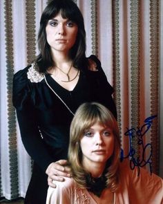 two women standing next to each other in front of a curtain with the words,