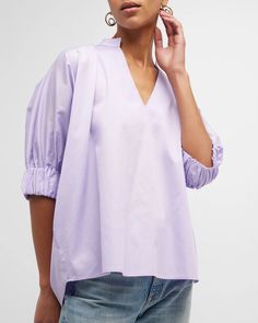 "Medina" Blouse is a this loose-fitting blouse that has become a best-seller. It features a V-neck collar and elbow-length sleeves with elasticized cuffs. Relaxed Fit. Material: 100% Cotton. Model 1 wears size 'S'. Model 2 wears size '1X'. Modern V-neck Blouse For Spring, Spring Blouse With 3/4 Gathered Sleeves, V-neck Blouse With Pleated Sleeves, V-neck Puff Sleeve Top For Work With Gathered Sleeves, Spring V-neck Top With Pleated Sleeves, Workwear Puff Sleeve Blouse With Smock Detail, Workwear Smock Blouse With Puff Sleeves, Puff Sleeve Smock Blouse For Work, V-neck Top With Smocked Cuffs For Spring