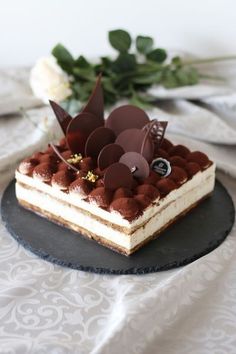 a piece of cake sitting on top of a black plate next to white flowers and greenery