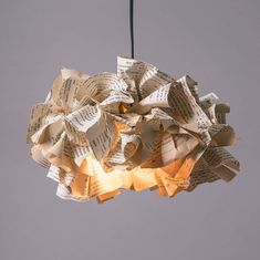 an origami light fixture made out of old sheet music sheets hanging from the ceiling