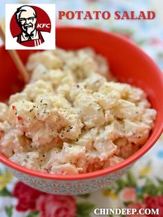 a red bowl filled with potato salad on top of a floral table cloth next to chopsticks