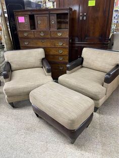 two chairs and a footstool in front of a dresser with other furniture on display