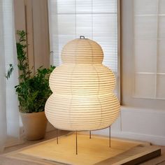 a white lamp sitting on top of a wooden table next to a potted plant