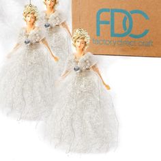 two white angel ornaments hanging from strings next to a cardboard box with the words factory direct craft on it