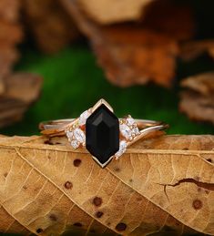 a black diamond ring sitting on top of a leaf