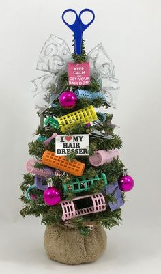 a small christmas tree with scissors and other items on it's top, in front of a white background