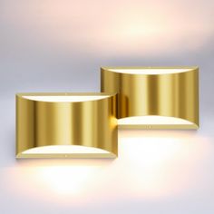 two lights that are next to each other on a white surface and one is gold