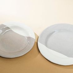 two white plates sitting next to each other on top of a brown tablecloth covered floor