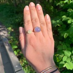 a woman's hand with a ring on it and a tree in the background