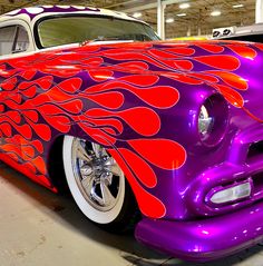 a purple and red car with flames painted on it's hood in a garage