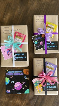 four wrapped gift boxes on a table with some books tied to the sides and ribbons around them