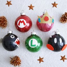 christmas ornaments with mario and luigi's faces on them, surrounded by pine cones