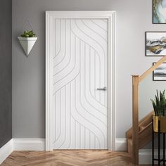 a white door in the corner of a room with stairs and pictures on the wall