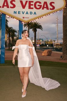 a woman standing in front of the las vegas sign wearing a white dress and veil