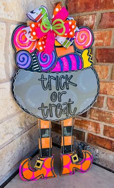 a sign that says trick or treat in front of a brick wall with orange and pink decorations