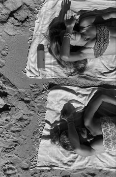 two young women laying on top of a beach towel