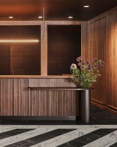 an elegant reception area with wood paneling and marble flooring, along with flowers on the counter