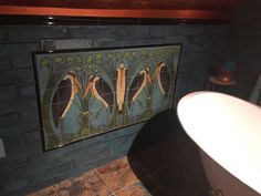 a bath tub sitting next to a painting on the side of a wall in a bathroom