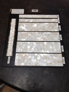 the back side of a table with some white tiles on it and two pieces of black plastic