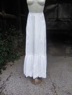 This is a white cotton petticoat from 1890's to 1905.  It features a bustle back with gathering in the rear.  There is a slight train with the longer back.  This petticoat has a double layer at the hem.  The top flounce is embroidered with  pretty little flowers and leaves and a scalloped edge.  The underlayer has a lace edged flounce.  There is a band of insertion lace at the top of the top flounce to run a ribbon.  This petticoat closes with a mother-of-pearl button.  There are 2 pinhead size Insertion Lace, Heavy Winter Coat, Little Flowers, Mother Of Pearl Buttons, Lace Edging, Scalloped Edge, Flowers And Leaves, Antique Victorian, Pink Cotton