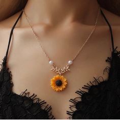 a woman wearing a necklace with a sunflower and pearls hanging from it's center