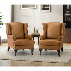 two brown chairs sitting next to each other on top of a rug