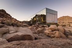 the glass building is surrounded by rocks and boulders