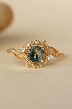 a close up of a gold ring with a green and white stone in the middle