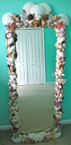 a mirror that has shells on it in front of a blue wall with a door