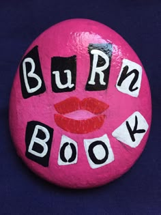 a pink rock with the words burn book on it and a red lips painted on it