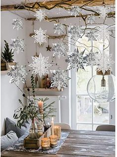 a dining room table with candles and snowflakes hanging from the ceiling