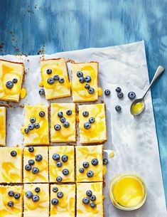 blueberry cheesecake squares are arranged on parchment paper with spoons next to them