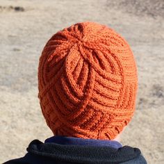 an orange knitted hat on top of a person's head