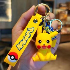 a hand holding a yellow pokemon keychain with a pikachu on it