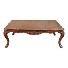 a wooden coffee table with carvings on the top and bottom, sitting against a white background