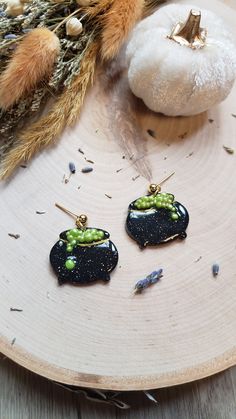 two small black earrings sitting on top of a wooden plate