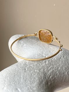 This bracelet is crafted from 925 silver with a matte gold plating and features a natural amber insert. The setting, meticulously handcrafted to precisely fit the selected stone offering a sleek and contemporary appearance that enhances the natural allure of the amber. It features a simple hook clasp for effortless wear. Designed with versatility in mind, this bracelet can enhance any outfit, blending seamlessly with both casual and formal attire. Its simple elegance is ideal for those who appre Adjustable Gold Gemstone Jewelry, Gold Adjustable Bracelet With Polished Finish, Modern Gold Jewelry With Oyster Bracelet, Modern Gold Plated Bracelets, Minimalist Adjustable Jewelry With Plating, Adjustable Gold Bracelets With Polished Finish, Modern Gold Bracelet In Brass, Minimalist Adjustable Plated Jewelry, Elegant Tarnish Resistant Brass Bangle