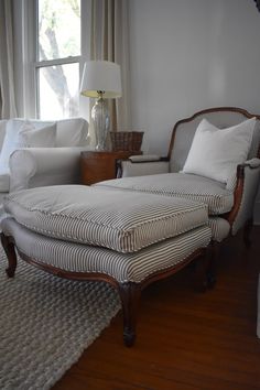 a chaise lounge chair sitting in front of a window next to a white couch