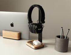 an apple computer, headphones and pen holder on a desk