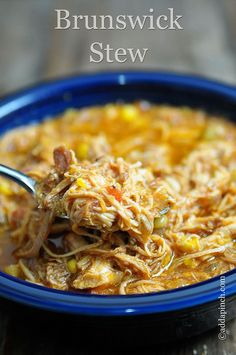 a blue bowl filled with pulled pork and corn soup on top of a wooden table