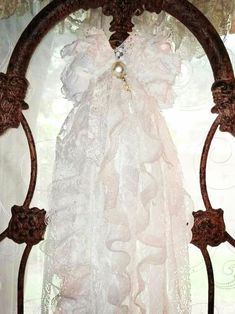 a white dress hanging on the side of a metal window sill in front of a curtain