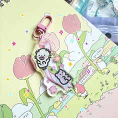 a hello kitty keychain hanging from a clip on top of a piece of paper