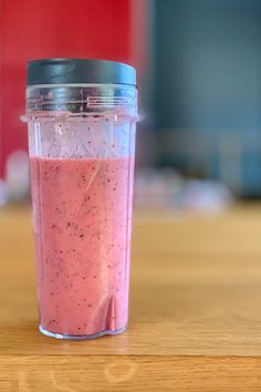 a pink smoothie in a plastic cup on a table