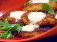 two crab cakes on a red plate with parsley garnish and sour cream