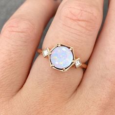 a woman's hand with an opal and diamond ring on top of her finger