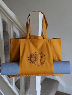 a yellow tote bag sitting on top of a stair rail next to a blue yoga mat