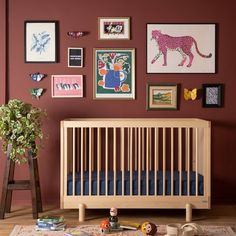 a baby's room with red walls and pictures on the wall, including a crib