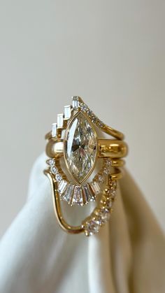 a close up of a gold ring on a white cloth with a diamond in the center