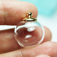 a person holding a tiny glass ball with a gold ring on it's finger