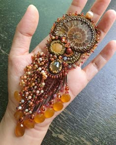 a woman's hand holding a piece of beaded jewelry with beads on it